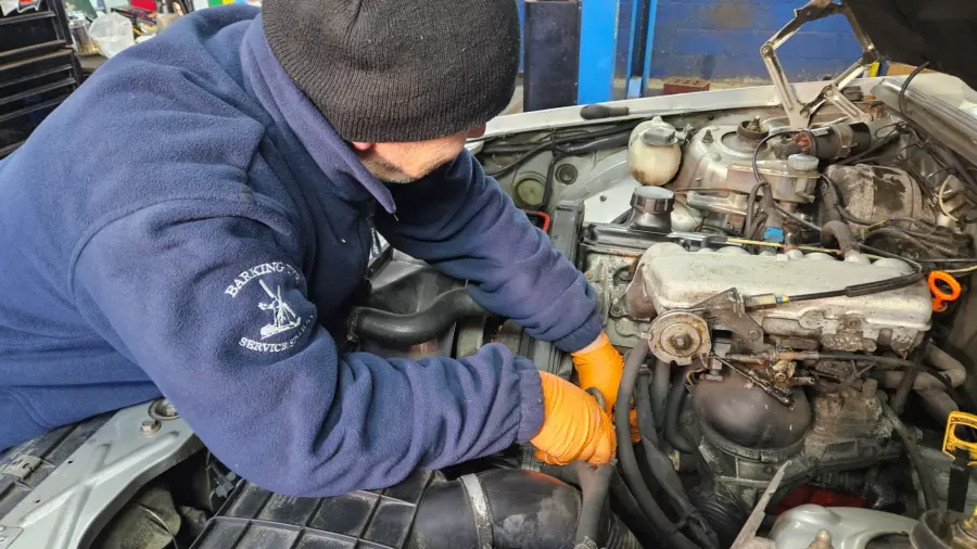 A mechanic working in the engine bay of a car